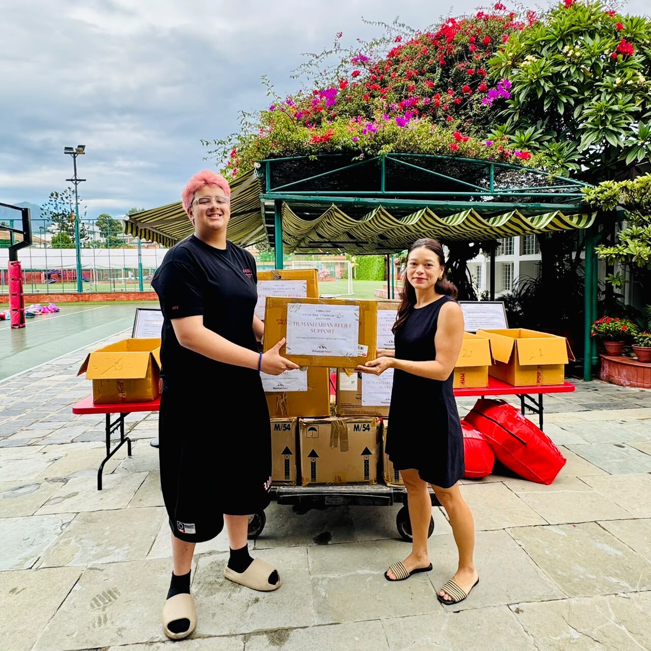 Ben Pokharel handing relief supplies to Ms. Anne McGuinness, Lincoln Service Learning Coordinator