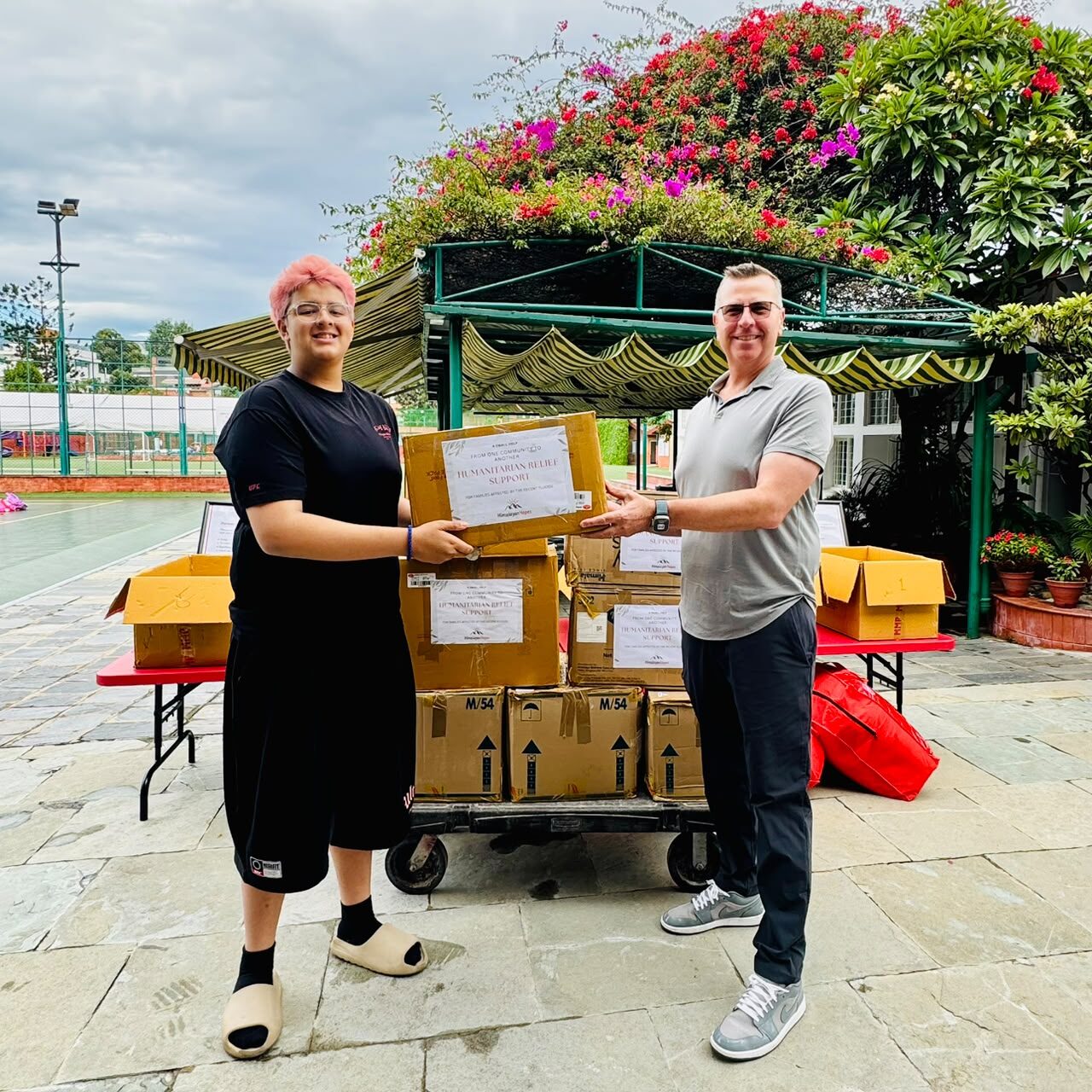 Ben Pokharel handing relief supplies to Mr. Dan Sharp, Principal of the Secondary School at Lincoln School