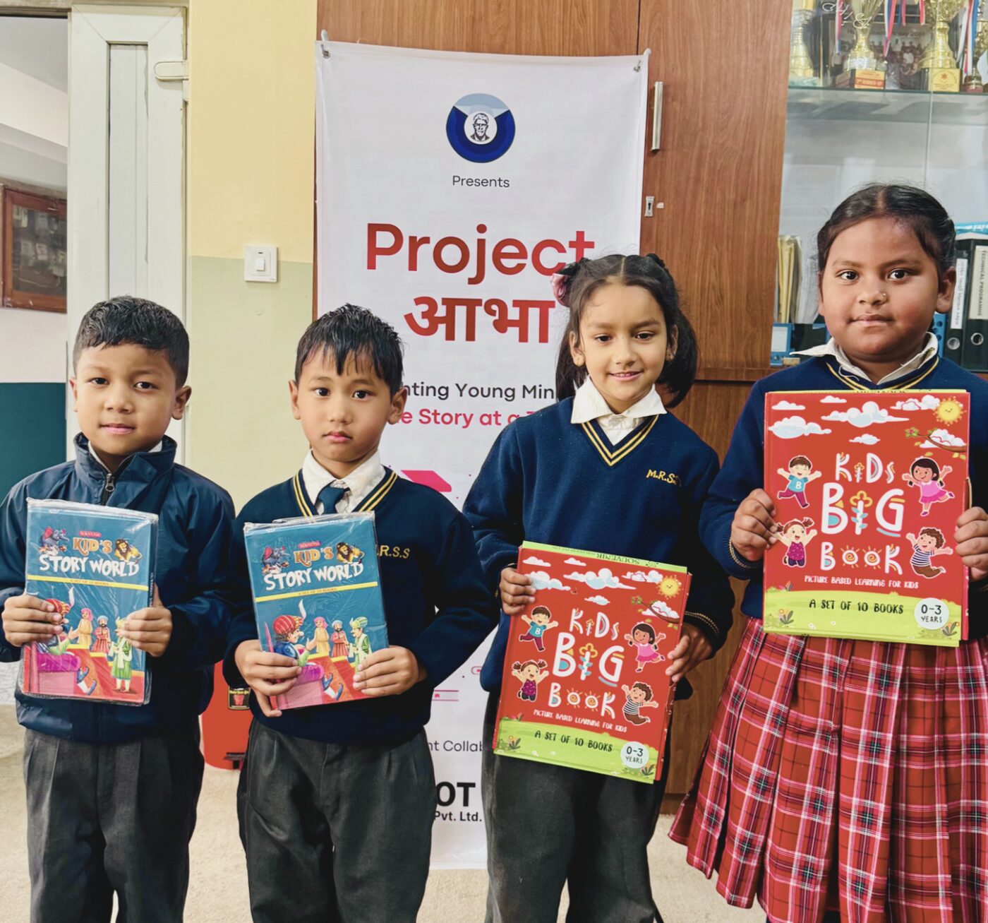 Young students holding donated storybooks and Kids Big Book sets