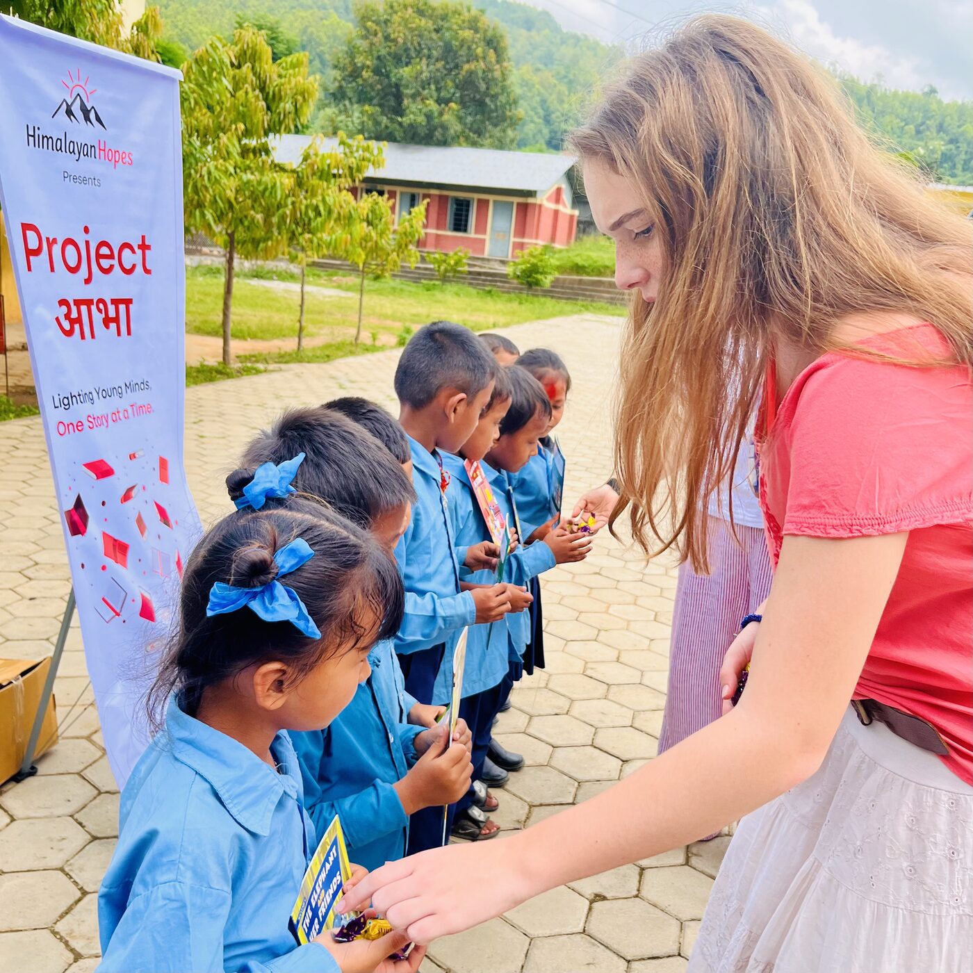 A volunteer handing books to young students